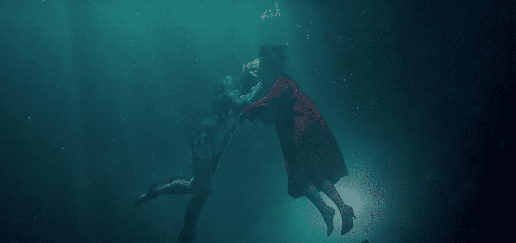 A woman and a sea creature embrace and share an underwater kiss