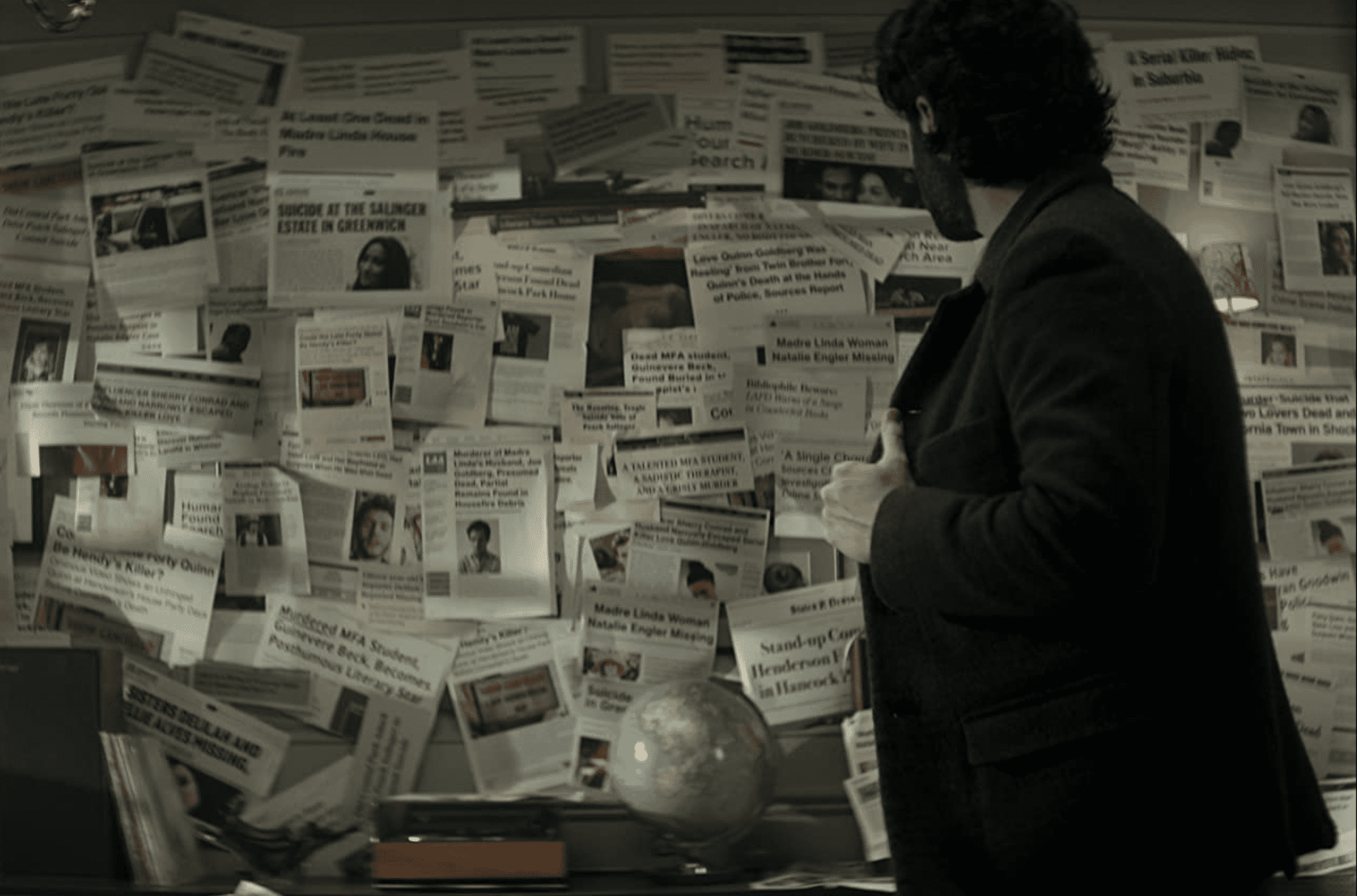 Joe stares at a board covered in newspaper clippings