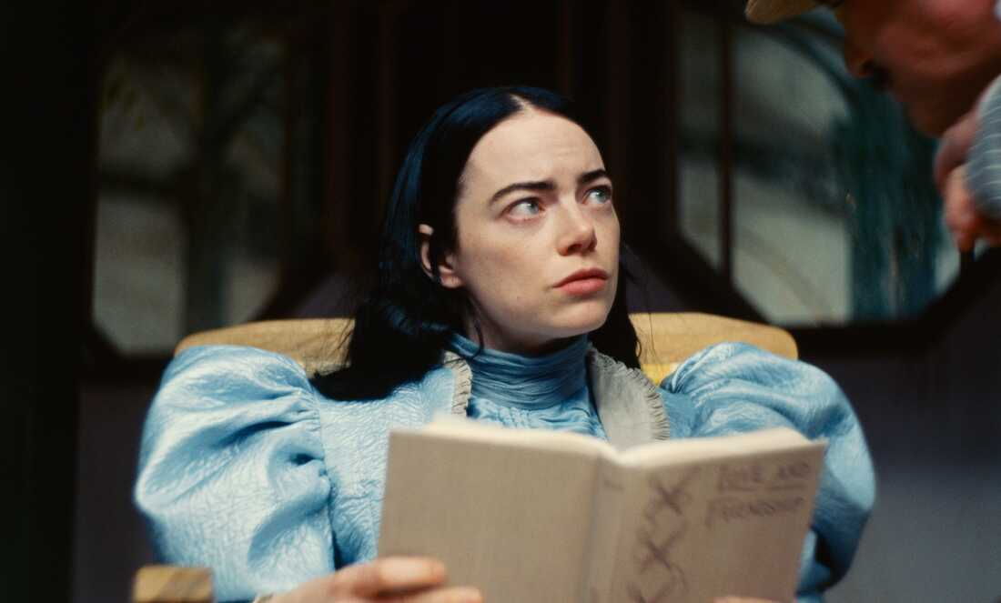 A woman sitting down holding a book looks to the side in this image from Element Pictures.