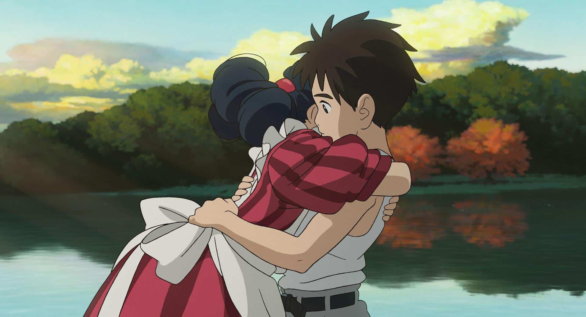 An anime girl hugging a boy in front of a lake in this image from Studio Ghibli.