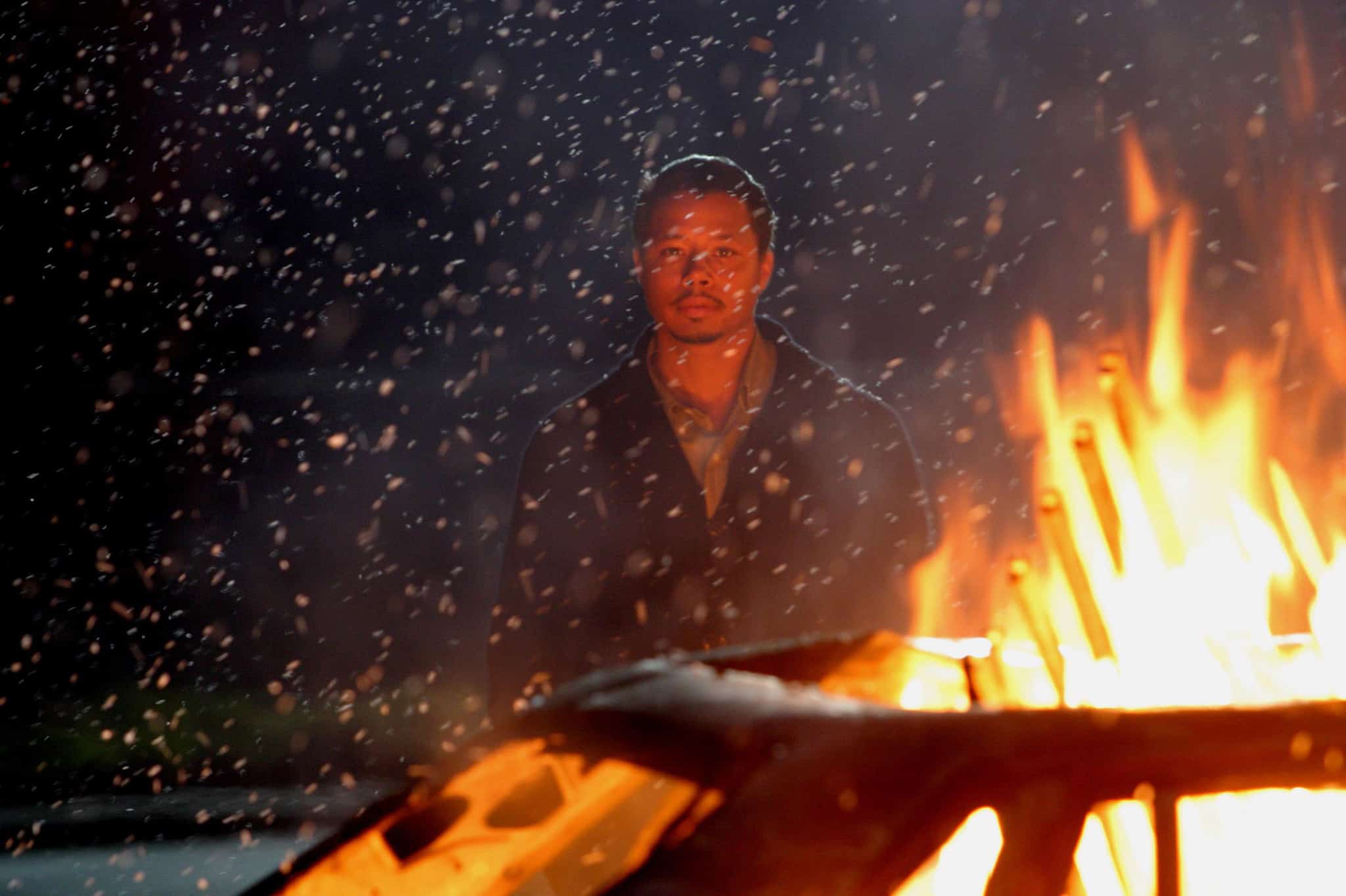 A man standing behind a burning car in this photo from Bob Yari Productions.