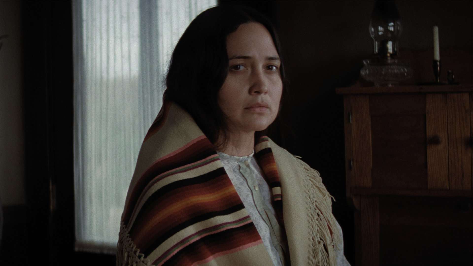 A young Native American woman wrapped in a blanket in this image from Apple Studios.