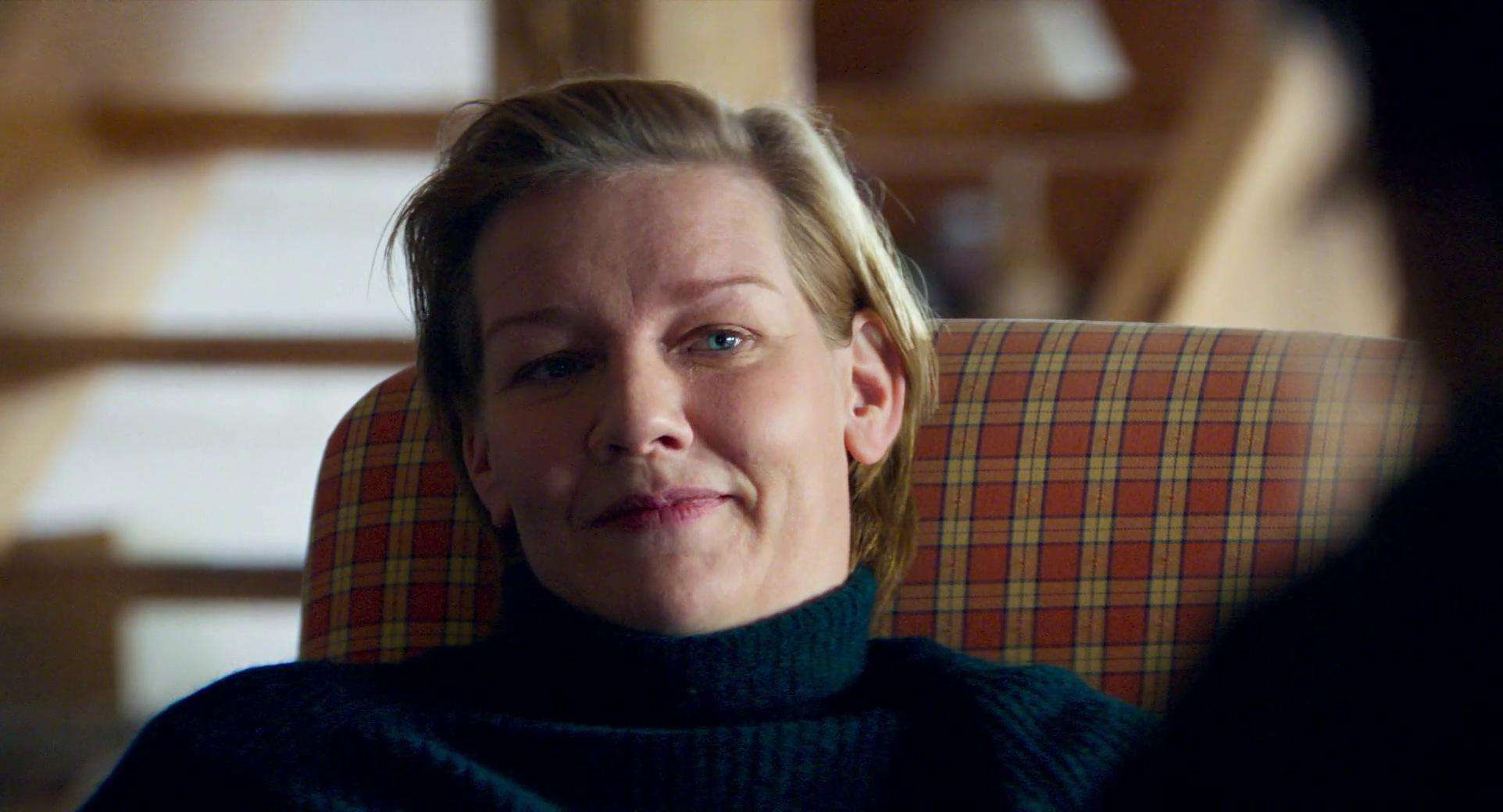 A short-haired woman smiles in an armchair in this image from Les Films Pelléas.