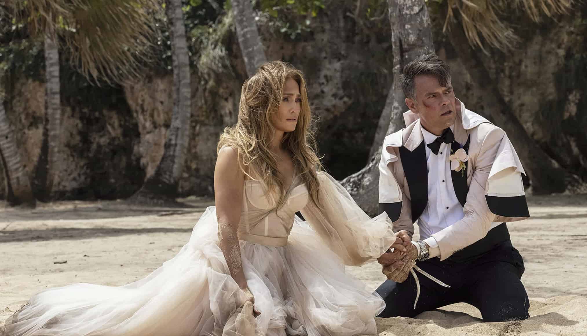 A woman and a man kneeling in the sand while wearing dirty and tattered wedding outfits in this image from Amazon Prime Video