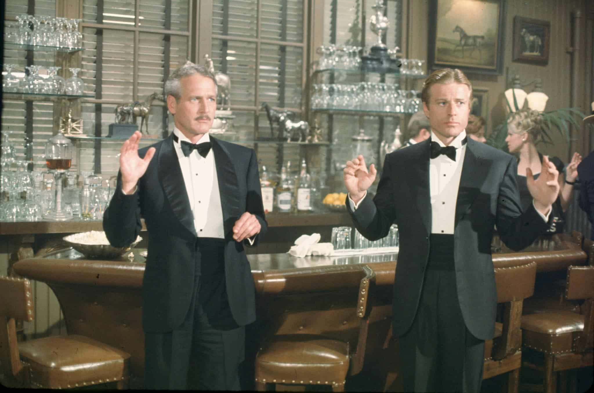 Two tuxedoed men hold up their hands in this photo from Universal Pictures.