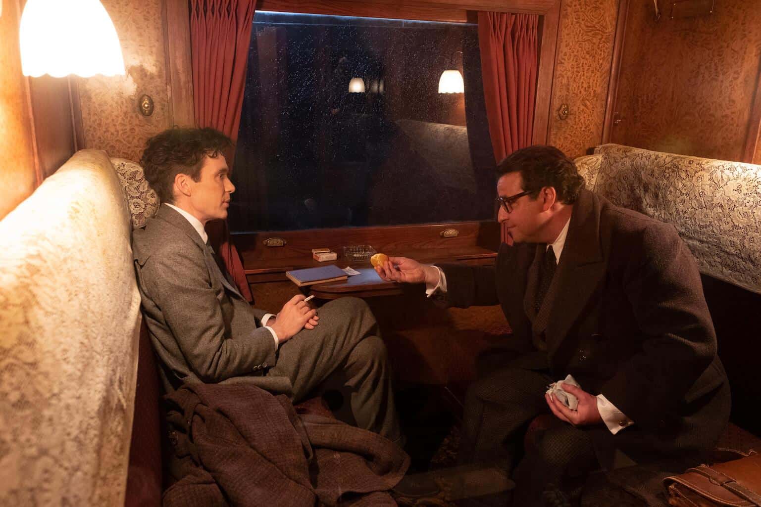 A man offers another man food on a train in this image from Universal Pictures.