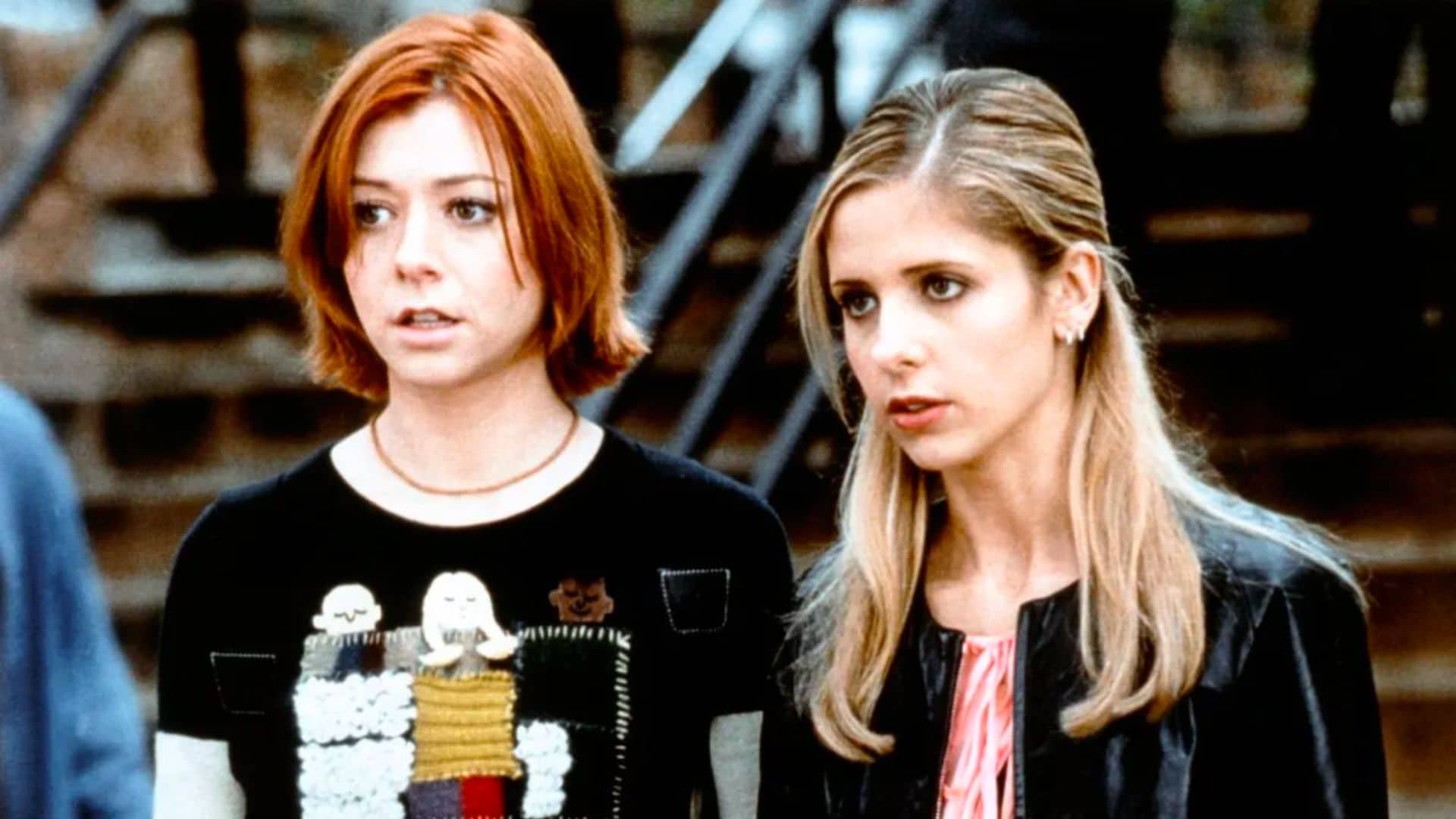 Willow and Buffy look intensely while standing in front of a flight of stairs in this image from Hulu.