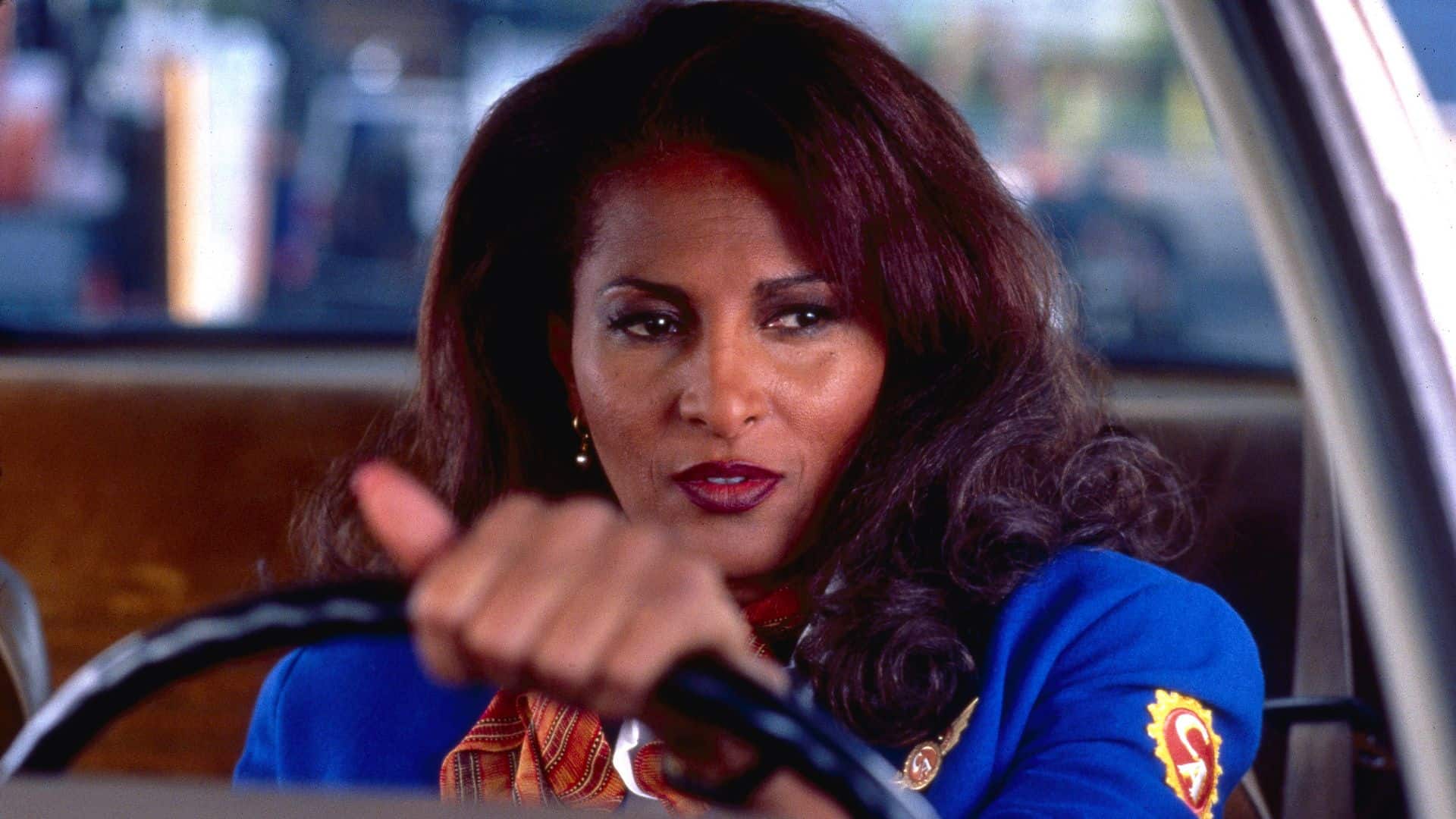 Jackie Brown driving a car in her flight attendant uniform in this image from Tubi