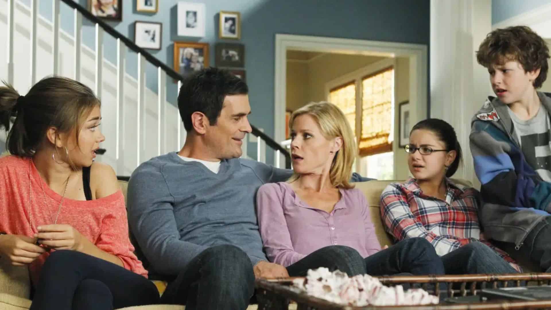 The Dunphy family looks at each other while sitting on a couch in their family room in this image from Hulu.