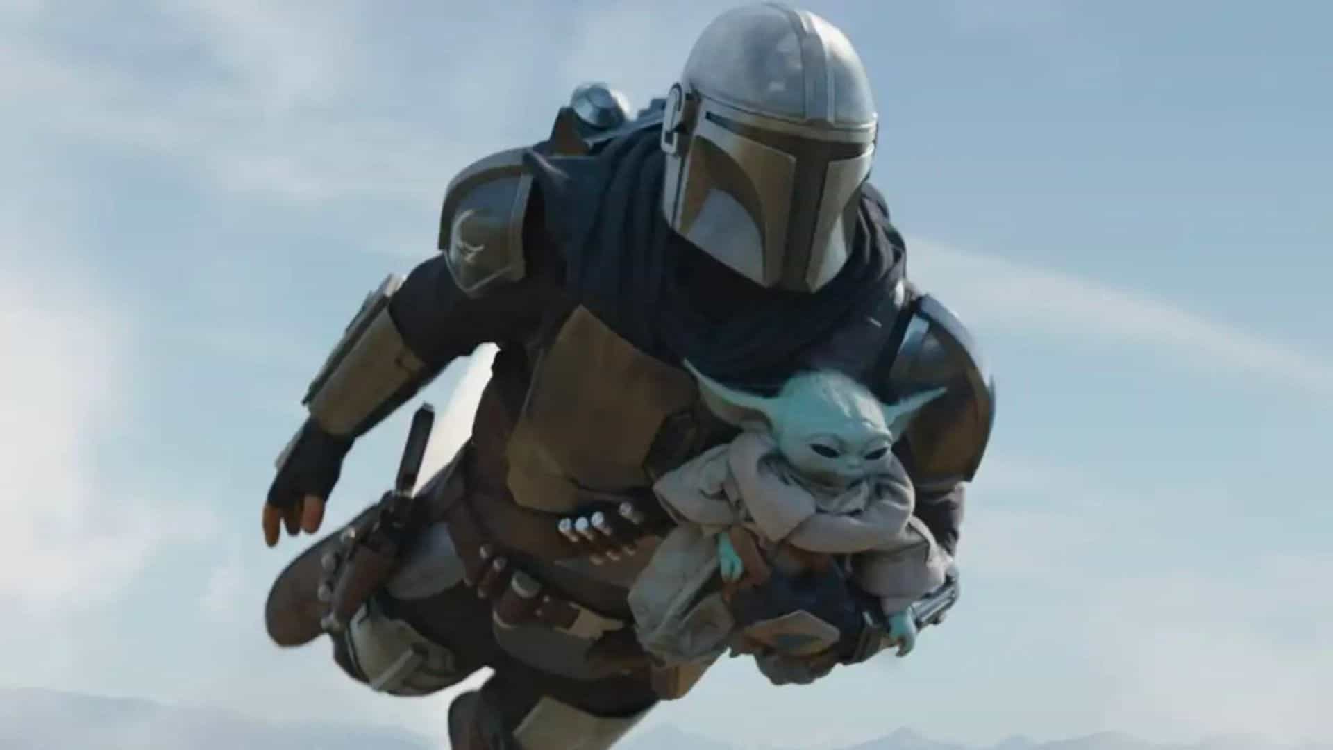 The Mandalorian, Din Djarin, flies with his jet pack carrying Grogu, The Child, in this image from Disney Plus.