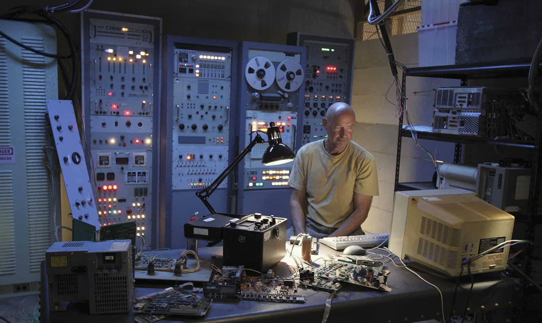 A man sits in a room full of electronics in this image from Hulu
