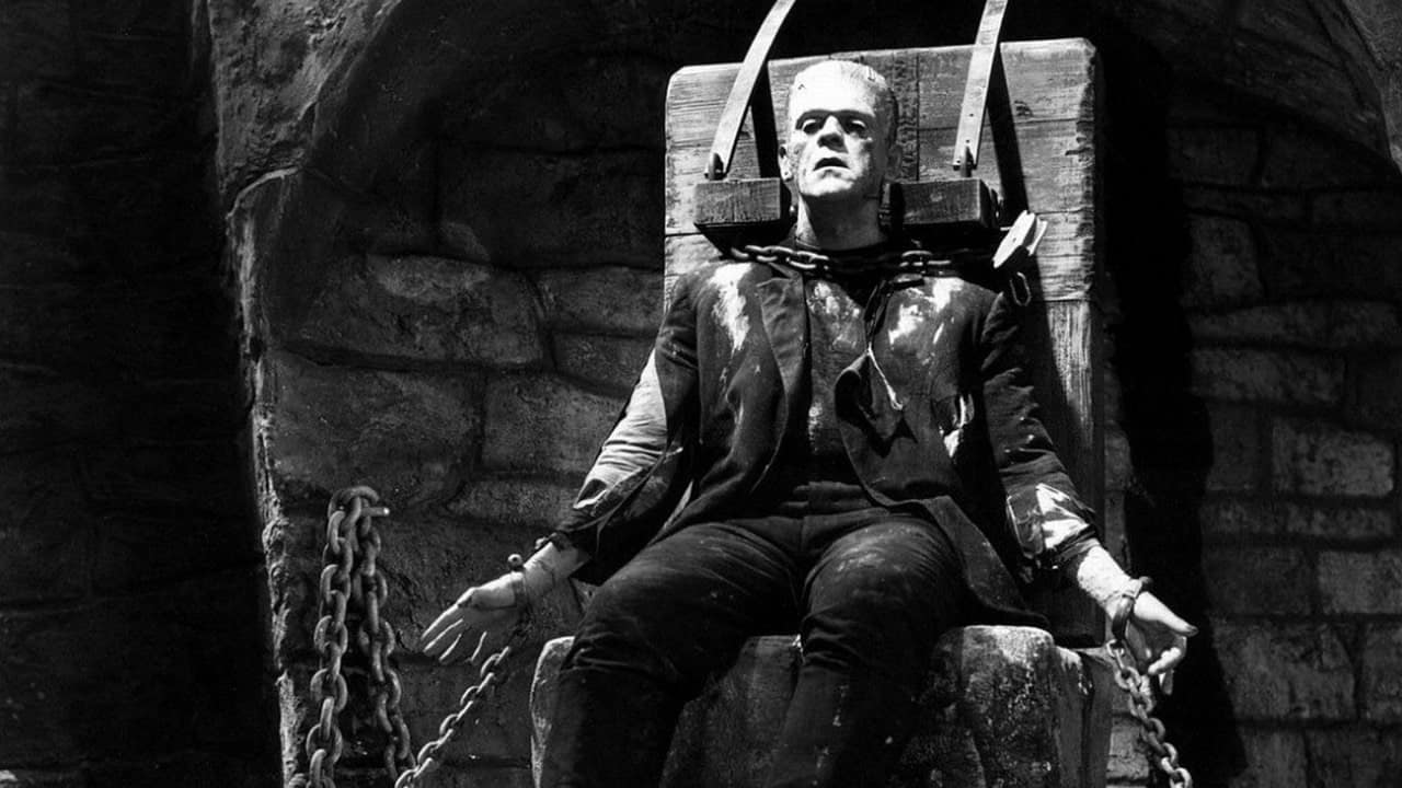 A monster sits in a chair with chains in this image from Universal Pictures