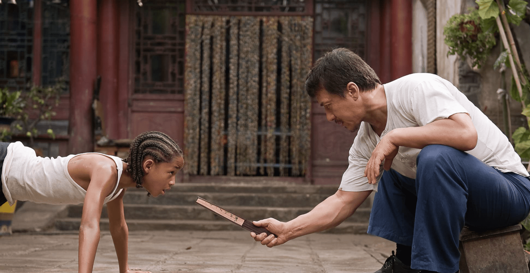 A teacher squats down to encourage a student to do a plank in this image from HBO Max.