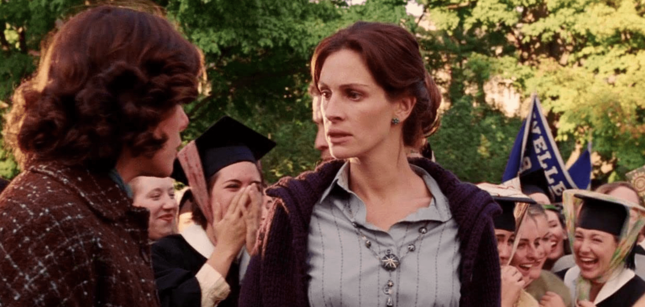 A female teacher is surrounded by students in graduation caps in this image from HBO Max.