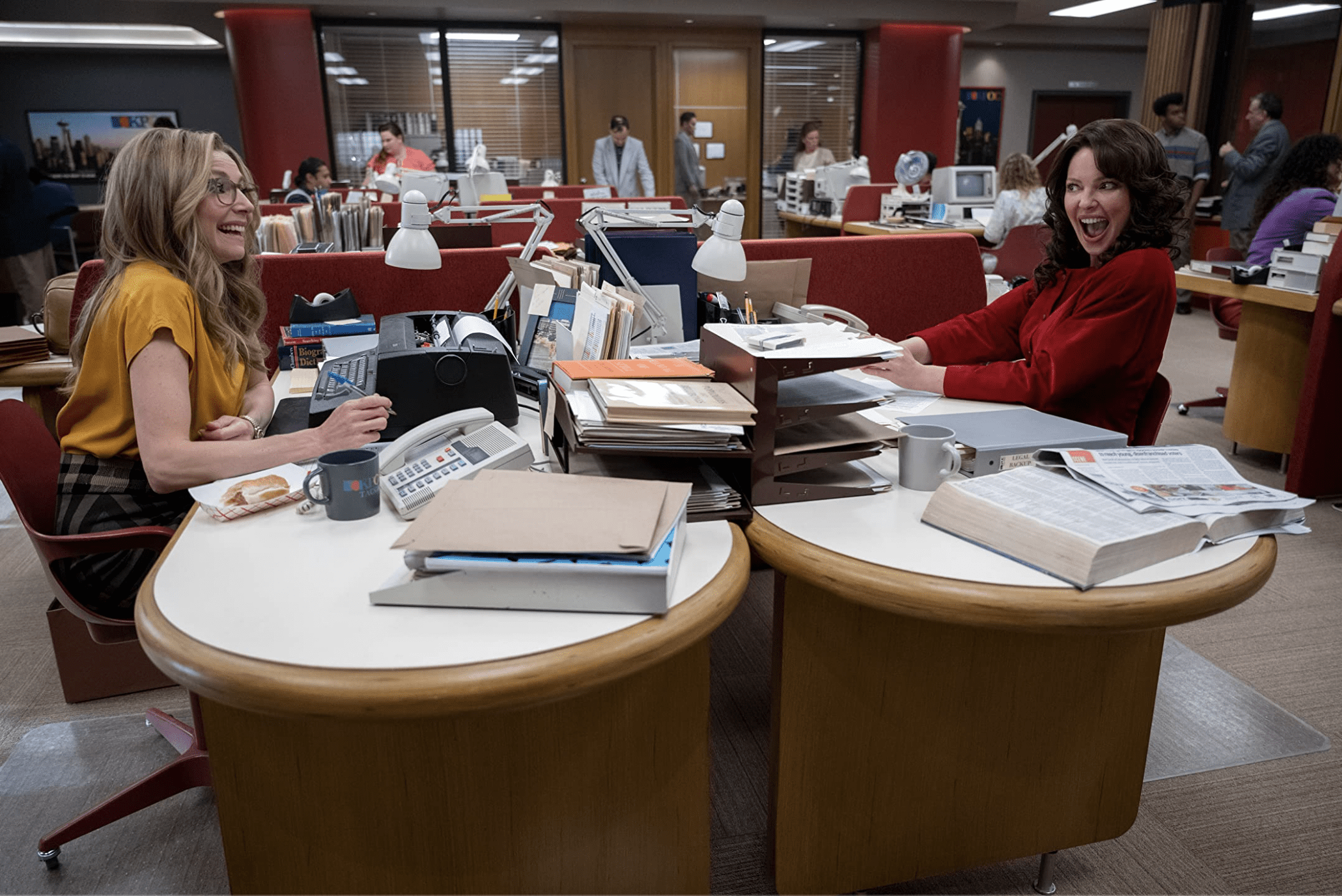 Two women laugh together in a newsroom in this image from Netflix