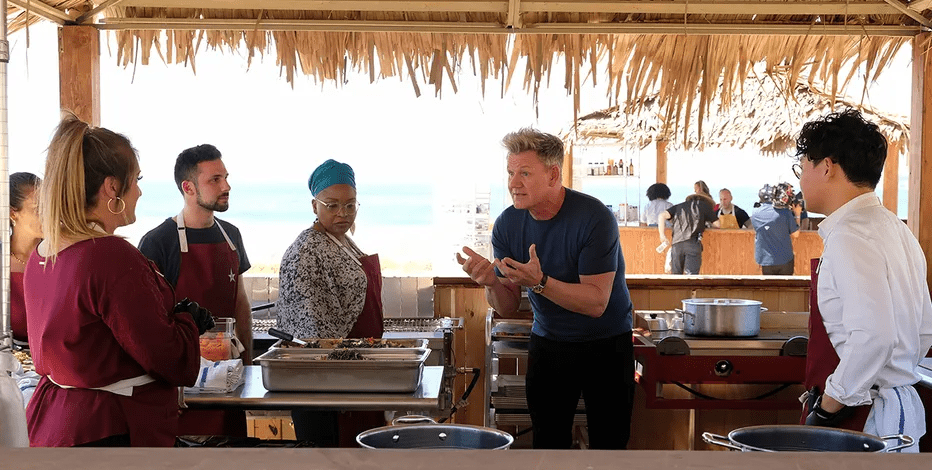 Gordon and the contestants cook outside on the beach in this image from Hulu