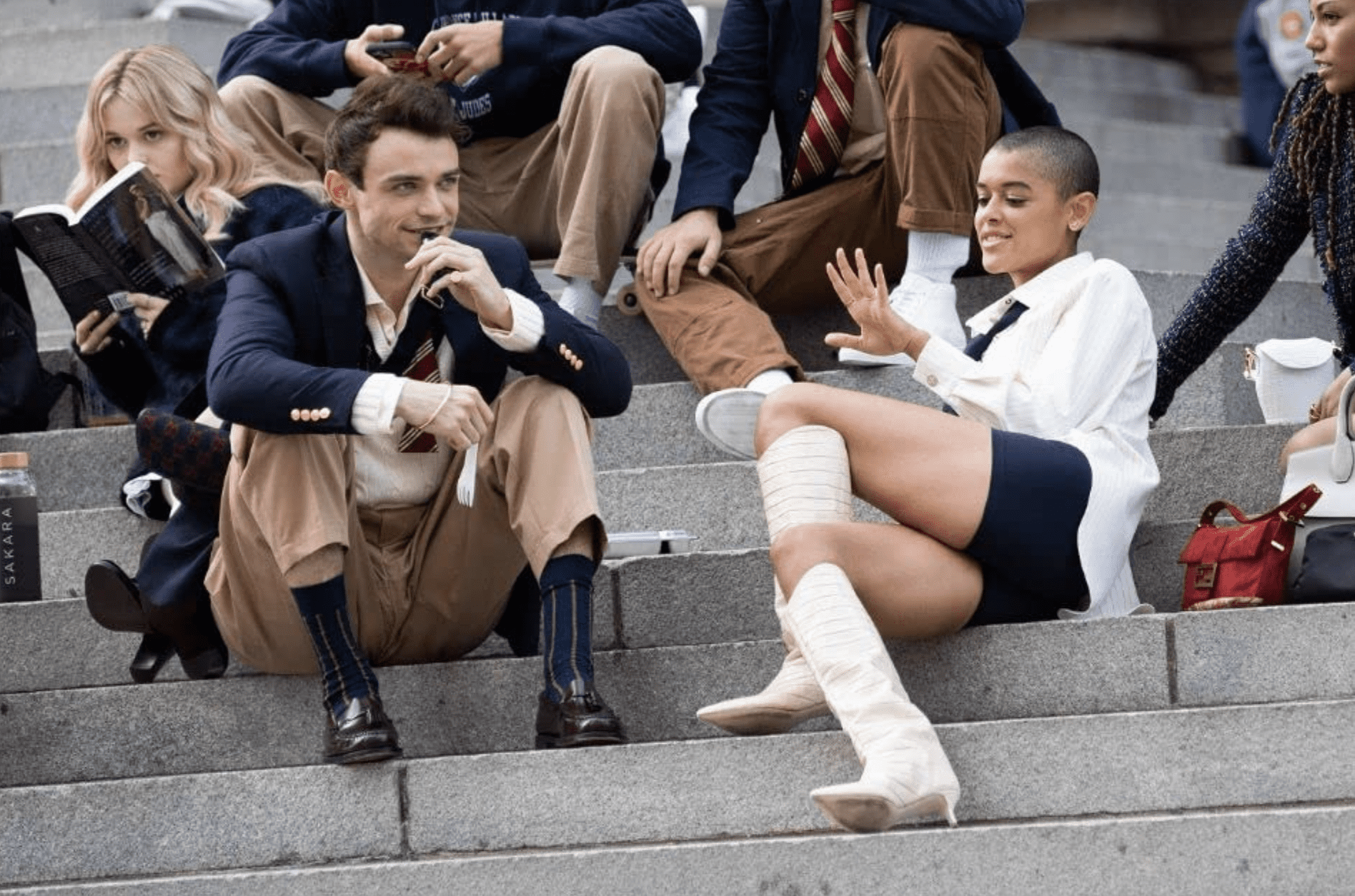 Two students sit on the Met steps in this image from HBO Max. 