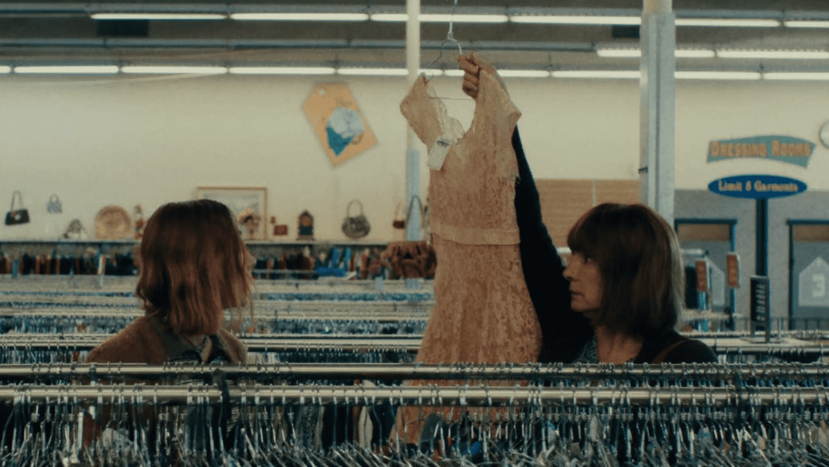 A mother holds up a thrifted dress for her daughter’s consideration in this image from Hulu