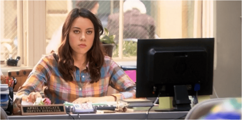 A girl in a rainbow plaid shirt sits at a desk in this image from Peacock