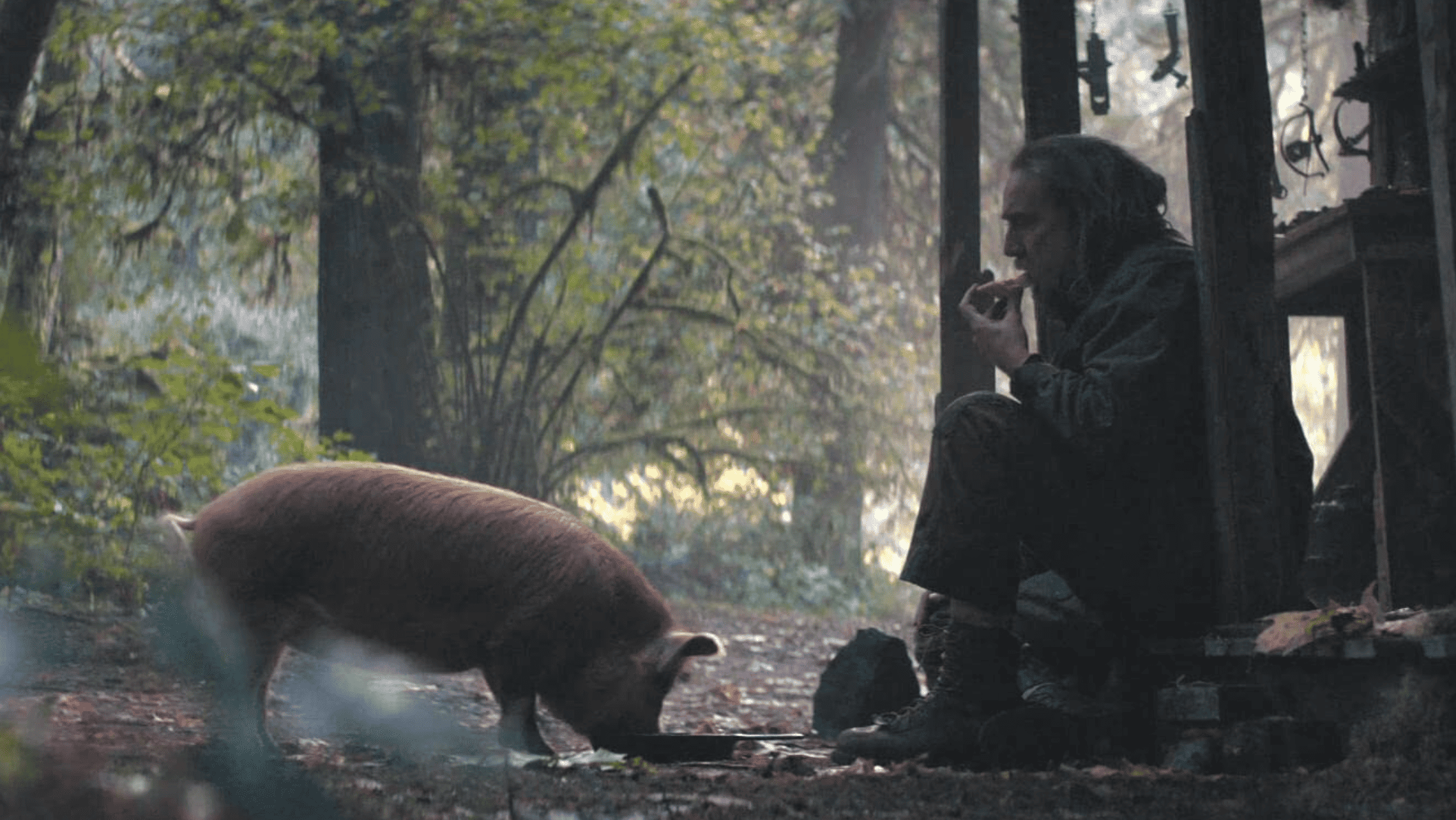 A man sits outside with his pig in this image from Hulu