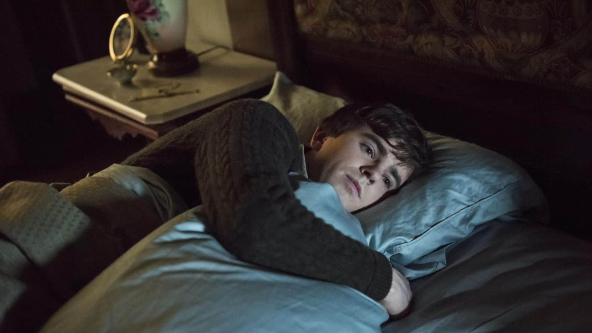 Freddie Highmore cuddles a pillow in bed in this image from Universal Television