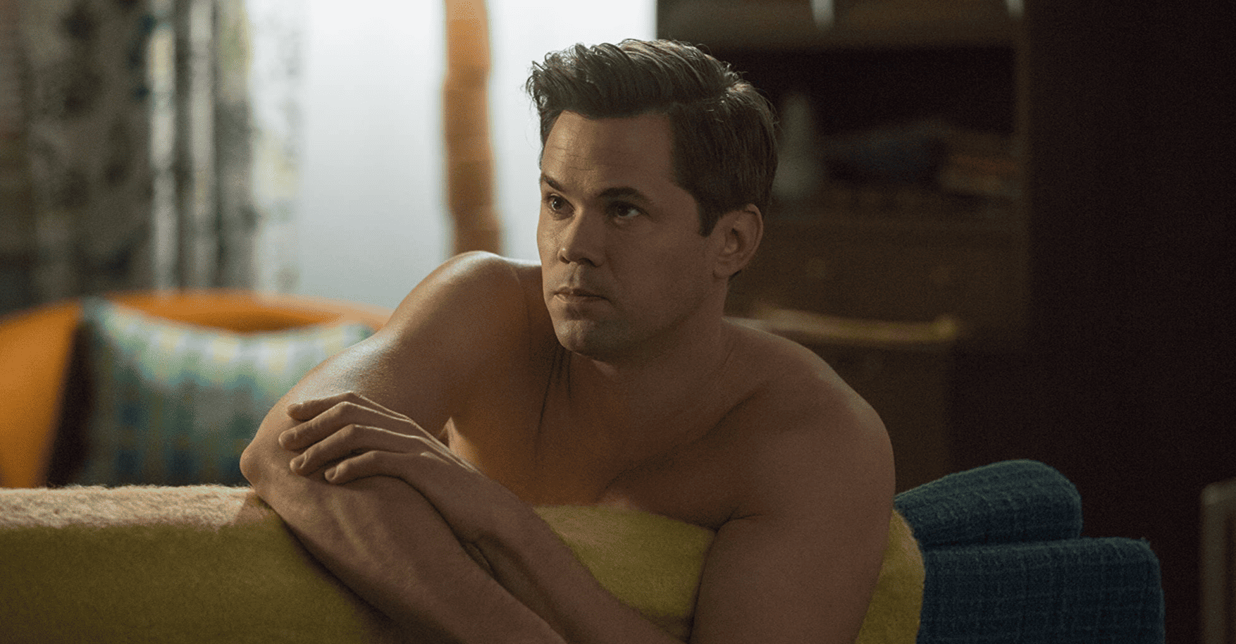 A shirtless Elijah sits dreamily on the couch in this image from Apatow Productions