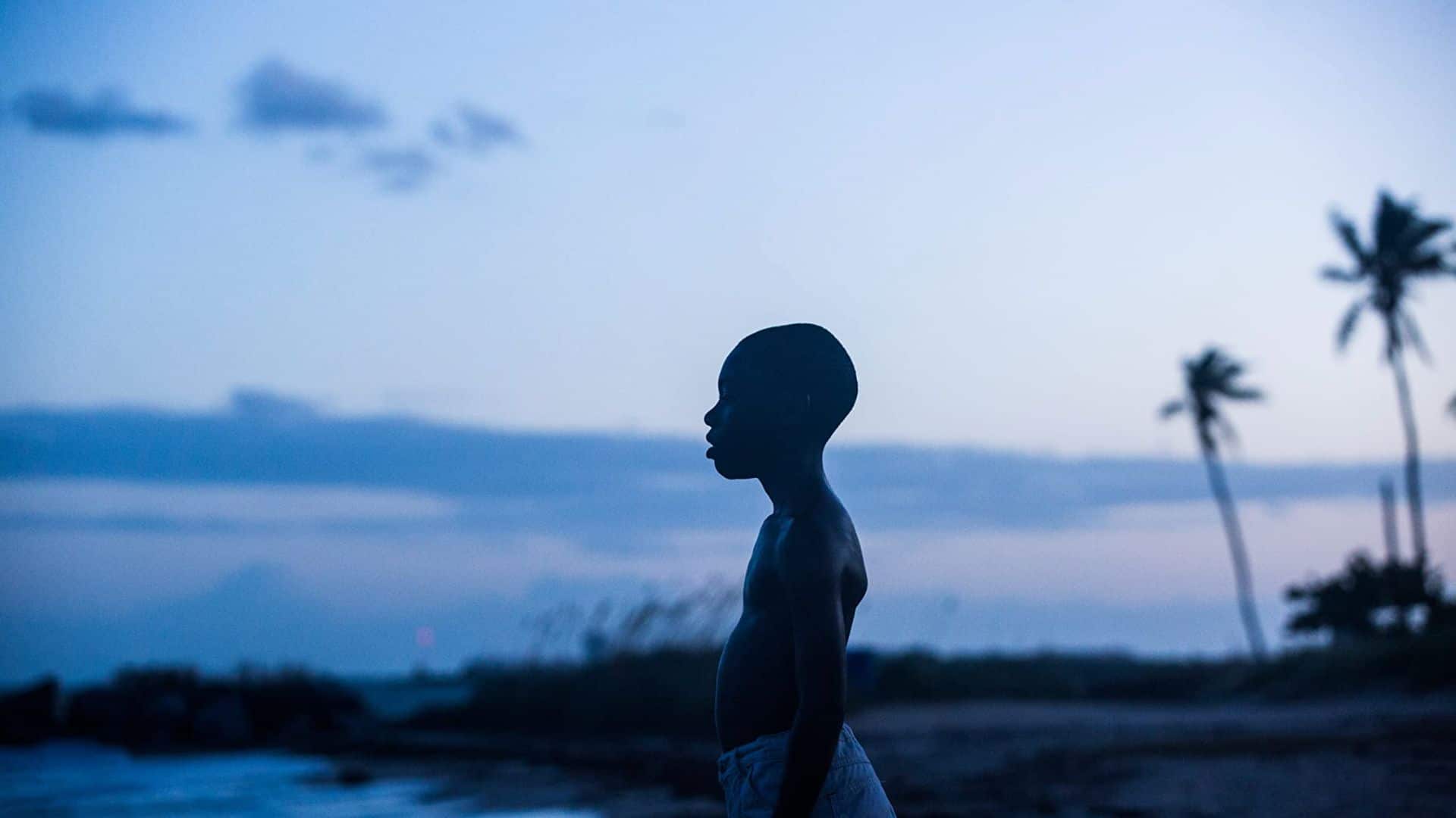 Little stands on the beach looking out at the water in this image from A24