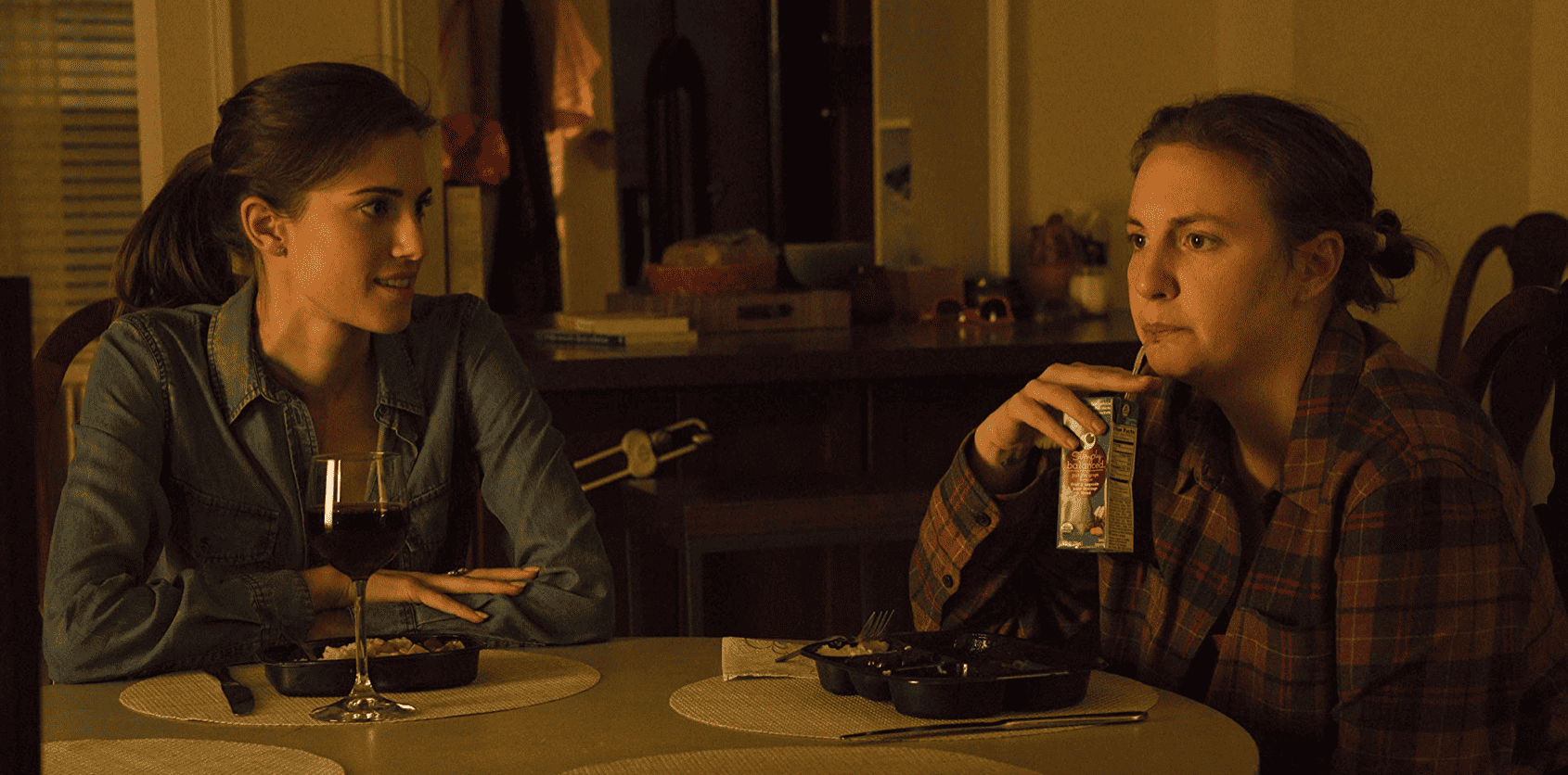 Marnie (Allison Williams) and Hannah (Lena Dunham) are having dinner together while drinking wine and a kids' juice box in this image from Apatow Productions