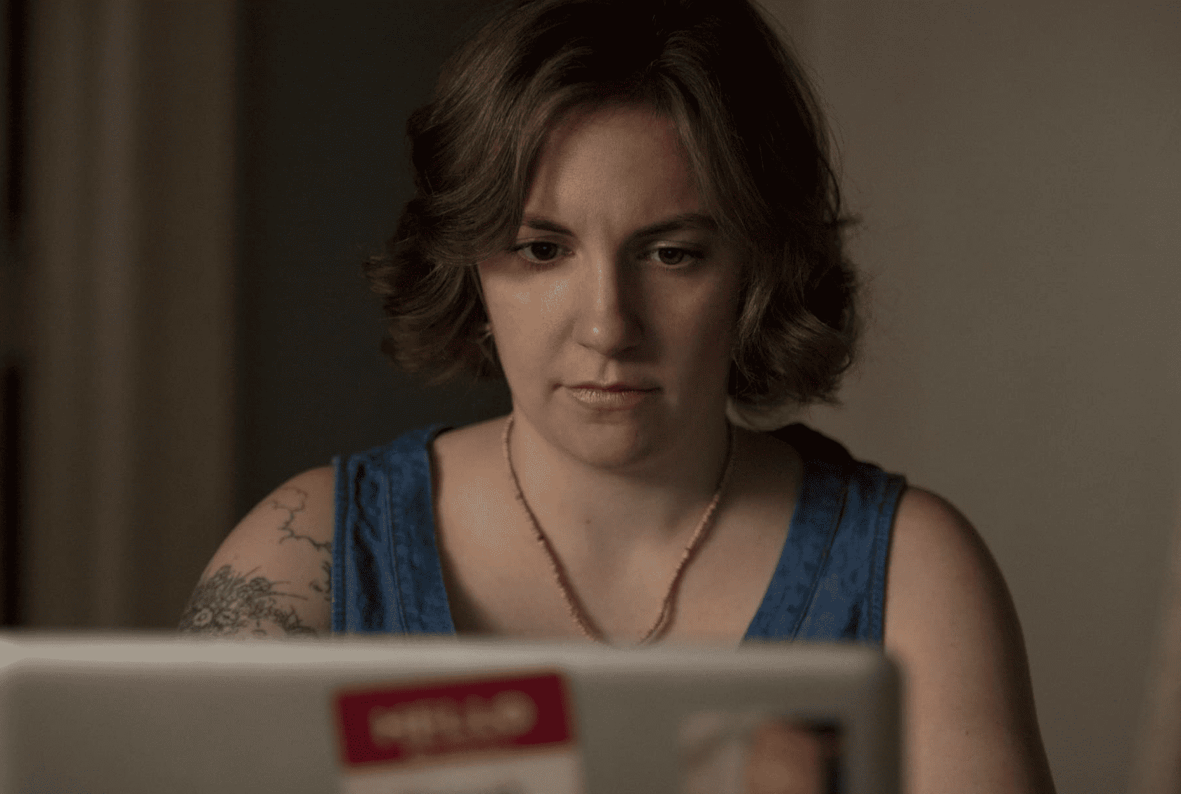Hannah sitting at her desk writing on her laptop in this image from Apatow Productions