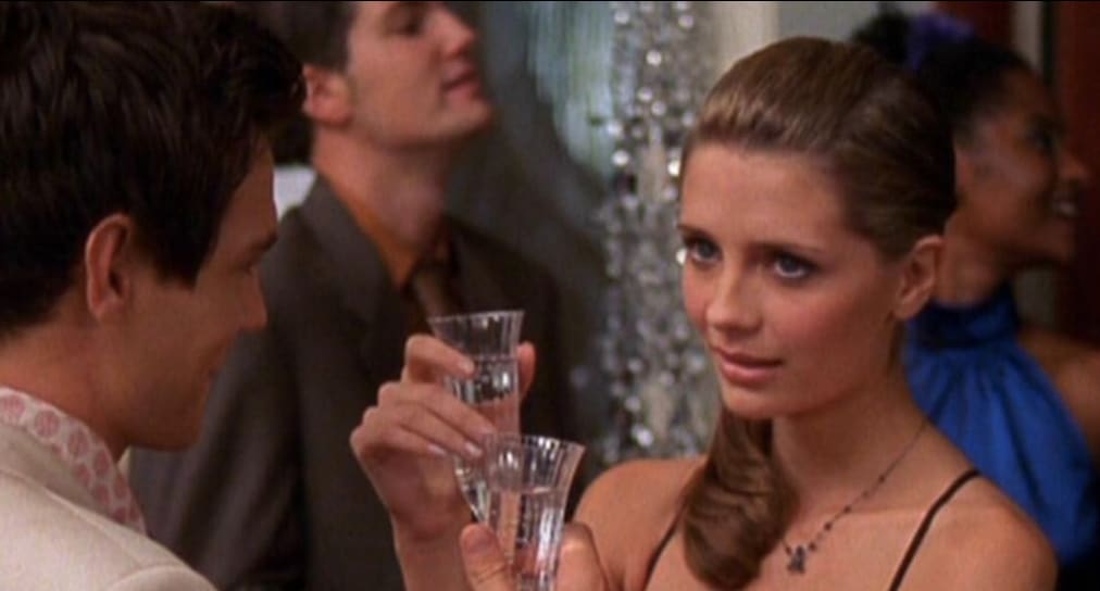 A woman holds Champagne while a man looks on in this image from Warner Bros. Studios.