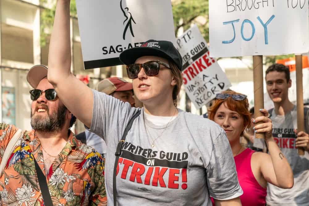 A crowd of WGA and SAG-AFTRA members holding up picket signs in this image from Shutterstock