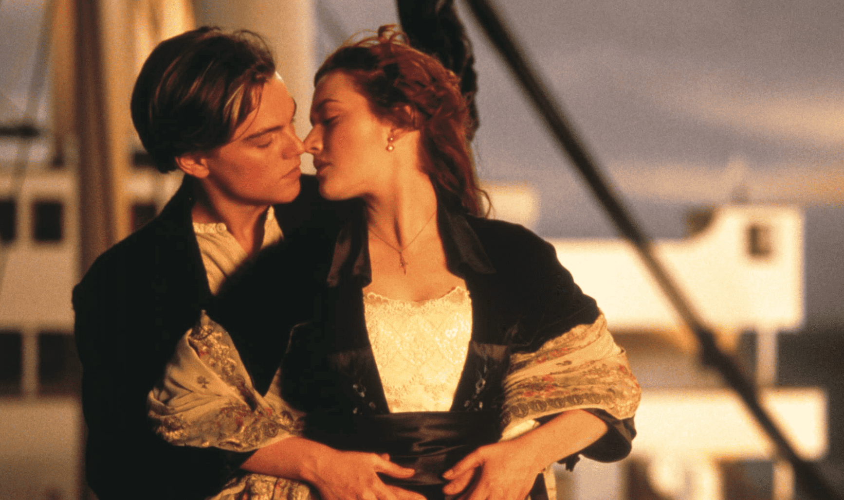 Jack standing behind Rose with his arms around her as they stand on the hull of the boat in this epic image from 20th Century Fox