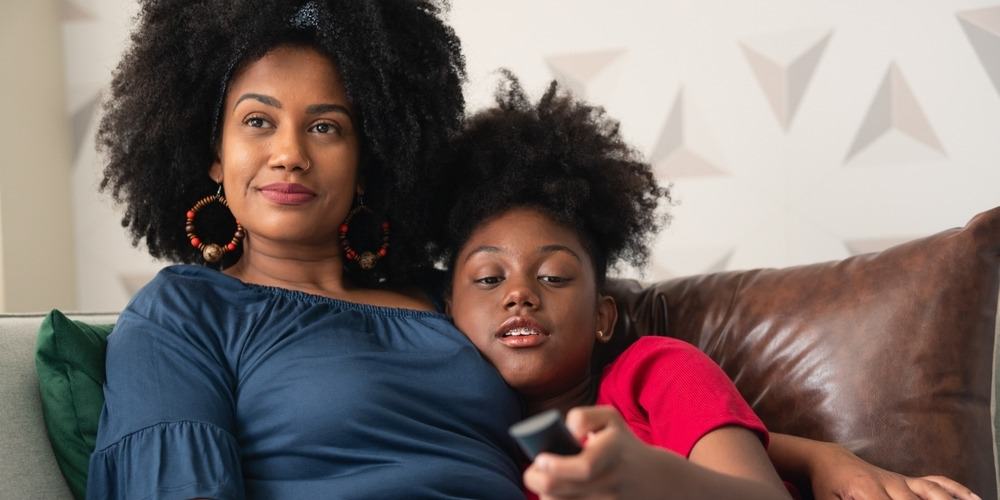 A mother and daughter watching TV together in this Shutterstock image