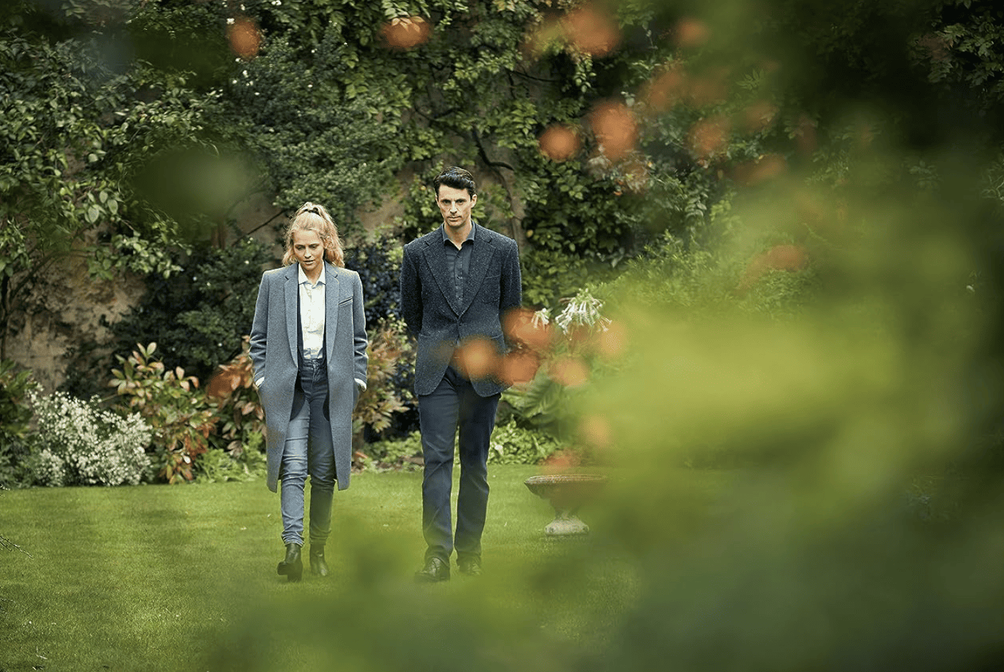 A woman and man walk through a garden in this image from Bad Wolf.