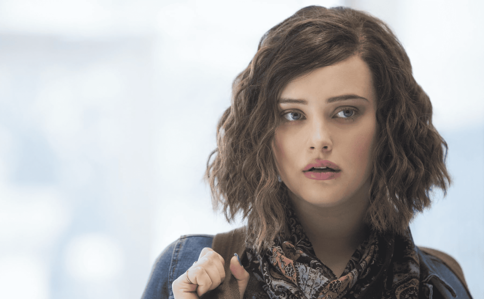 Katherine Langford as Hannah Baker holds a backpack strap with one hand in this image from July Moon Productions.