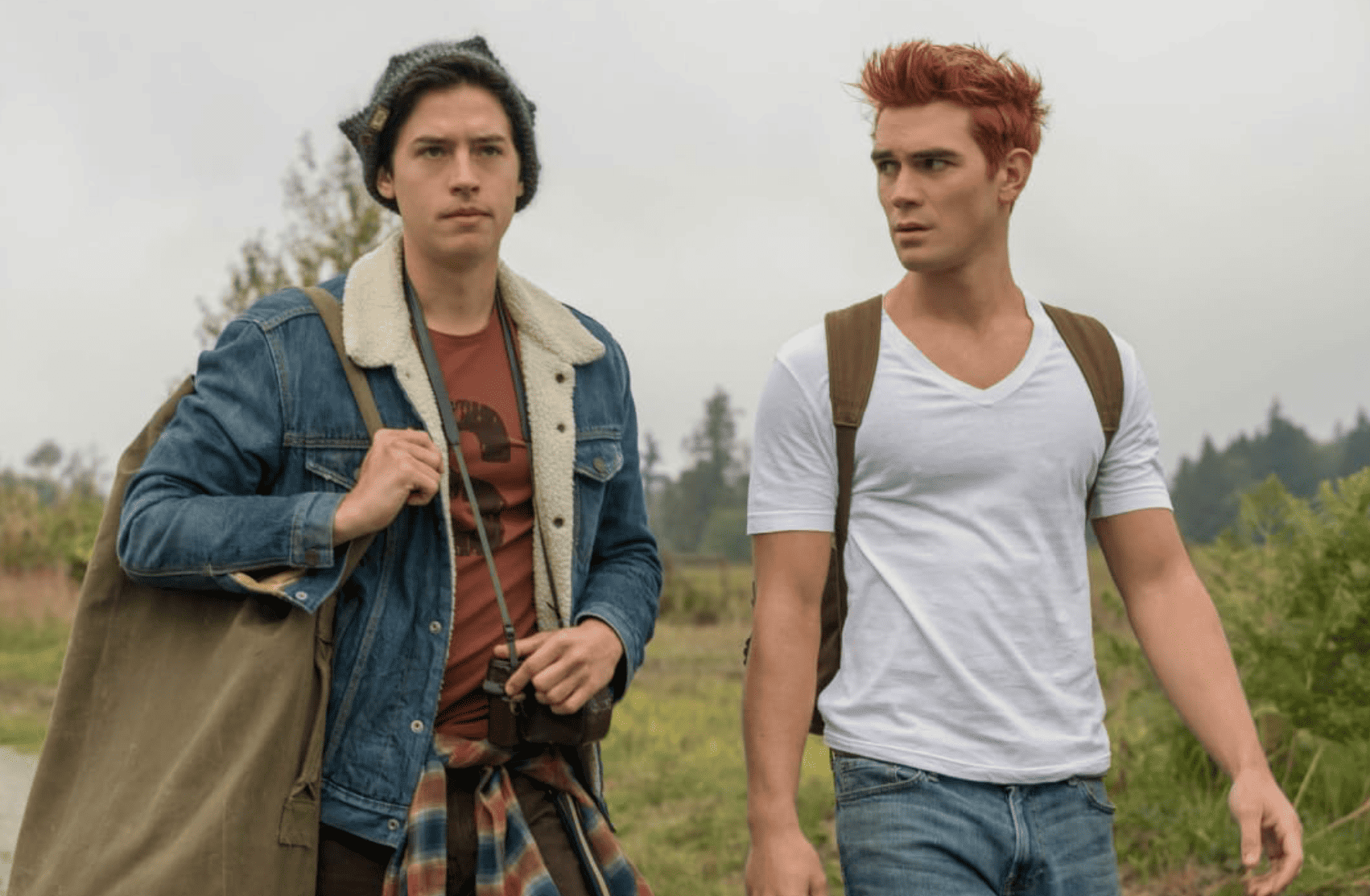 Cole Sprouse and K.J. Apa as Jughead and Archie, respectively, walk through a field in this image from Berlanti Productions.
