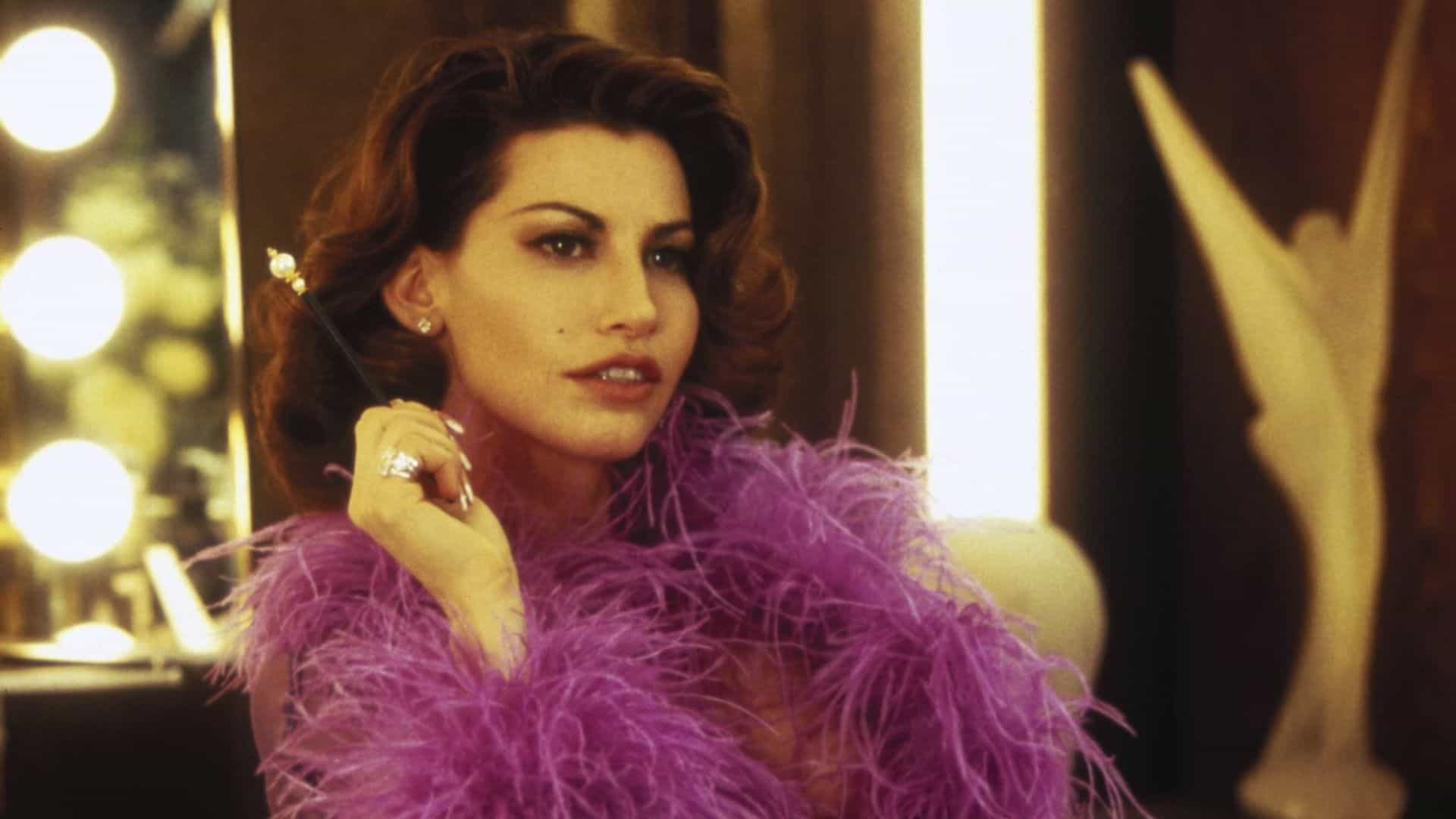 Gina Gershon in a purple robe with feathers in this image from Carolco Pictures
