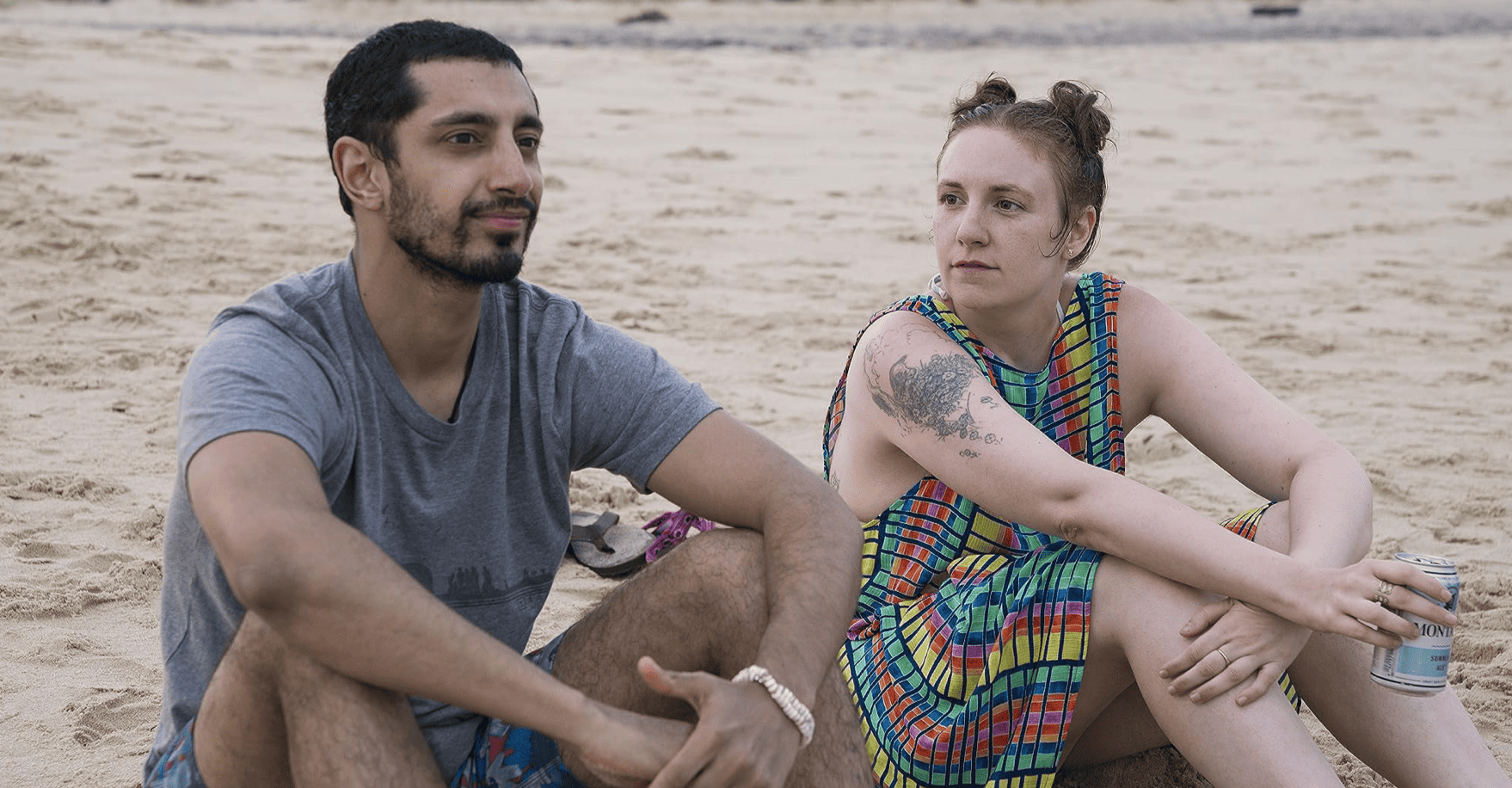 Hannah (Lena Dunham) stares longingly at Paul-Louis (Riz Ahmed) while sitting at the beach with drinks in hand in this image from Apatow Productions.