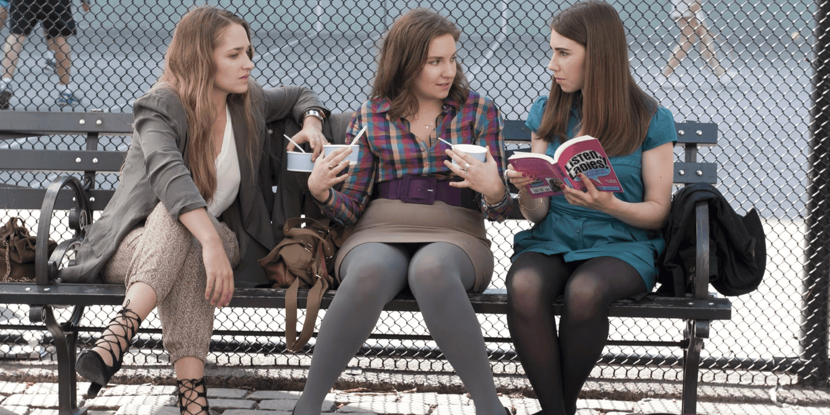 Jemina Kirke, Lena Dunham, and Zosia Mamet sitting on a park bench holding books and ice cream cups in this image from Apatow Productions