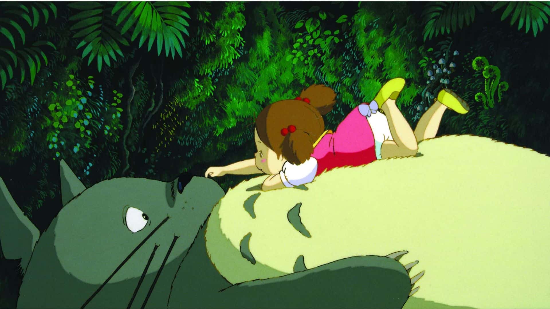 Mei lies on Totoro’s belly in this image from Studio Ghibli.