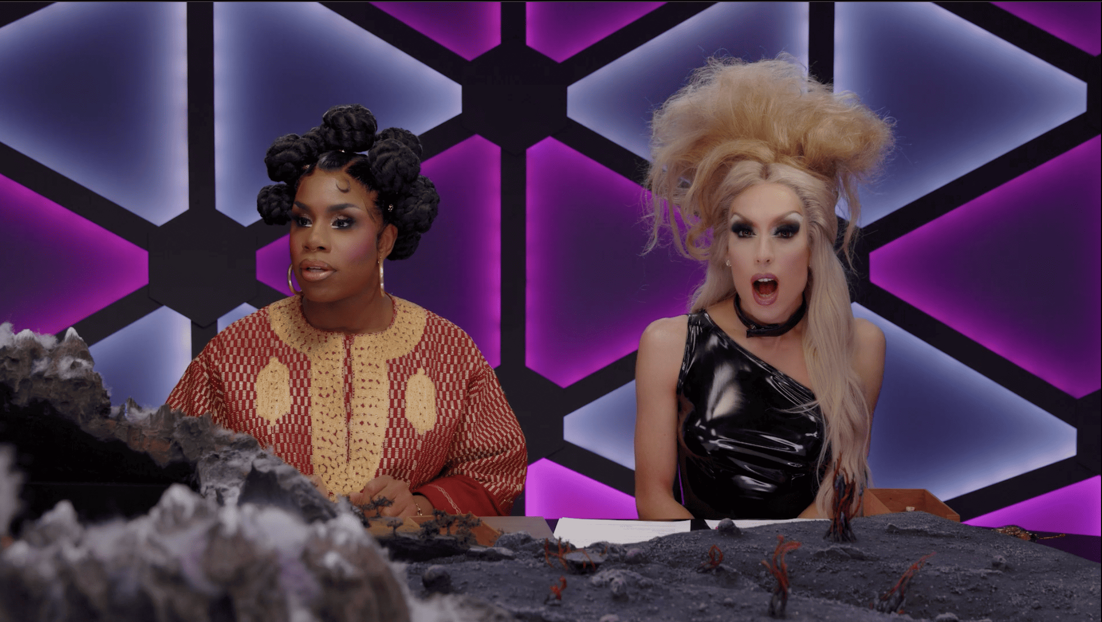 Two drag queens sit next to each other in this image from Dropout