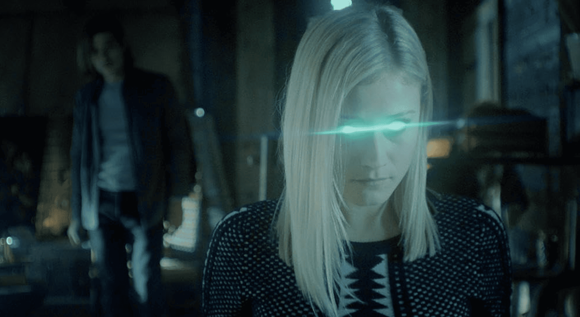 Olivia Taylor Dudley looks possessed with green lasers coming out of her eyes while Jason Ralph slowly approaches from behind in this image from McNamara Moving Company.