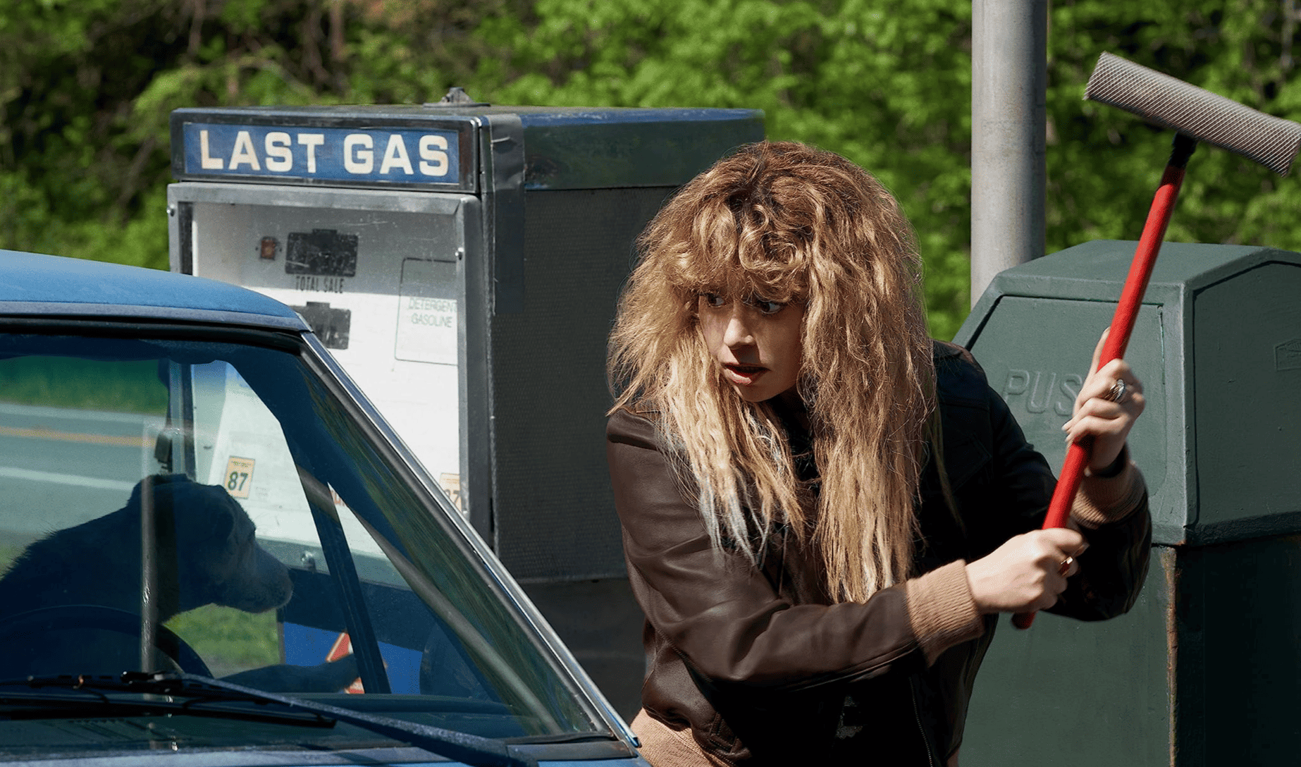 Natasha Lyonne holds a windshield cleaner at a gas station in this image from Animal Pictures.