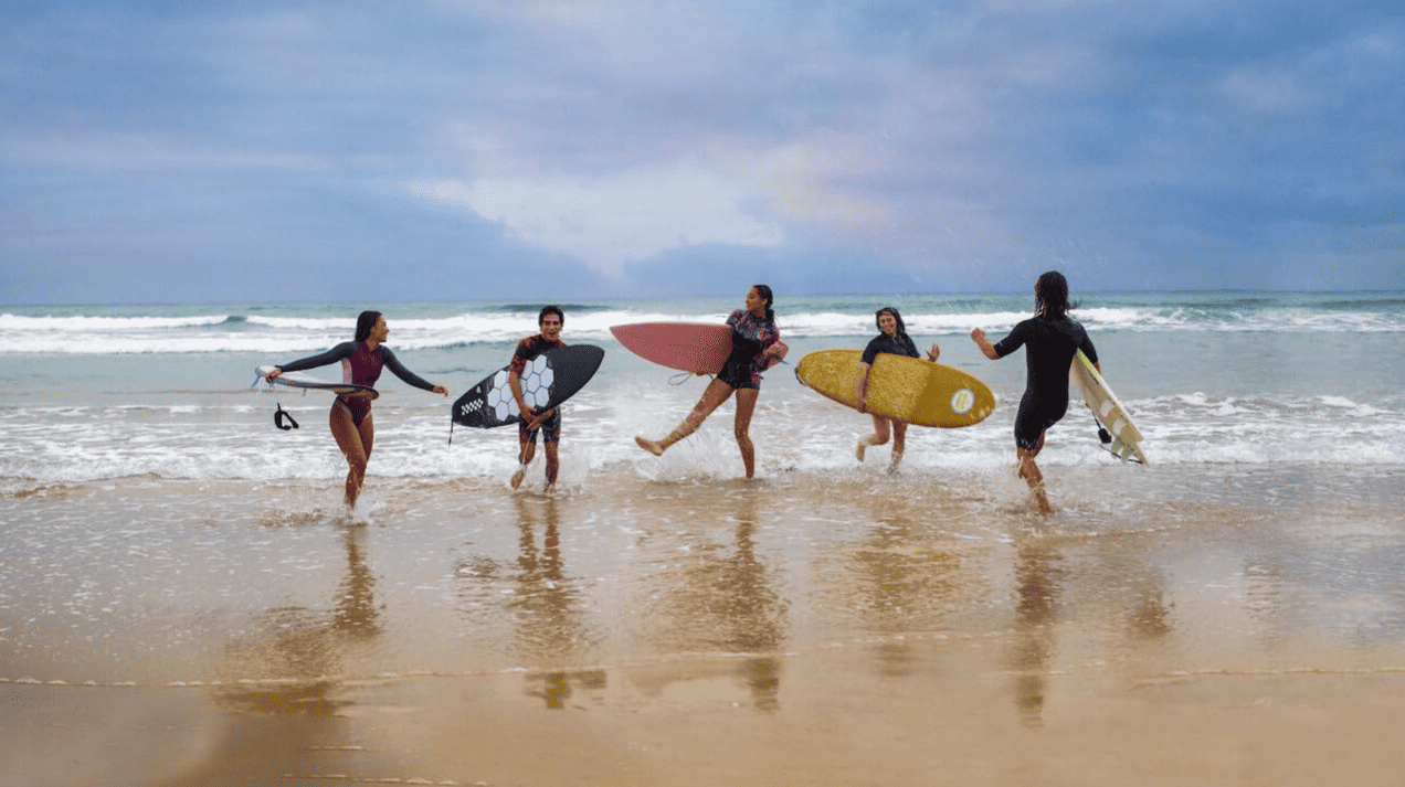 Five friends with their surfboards splashing in low tide in this image from Werner Films Productions