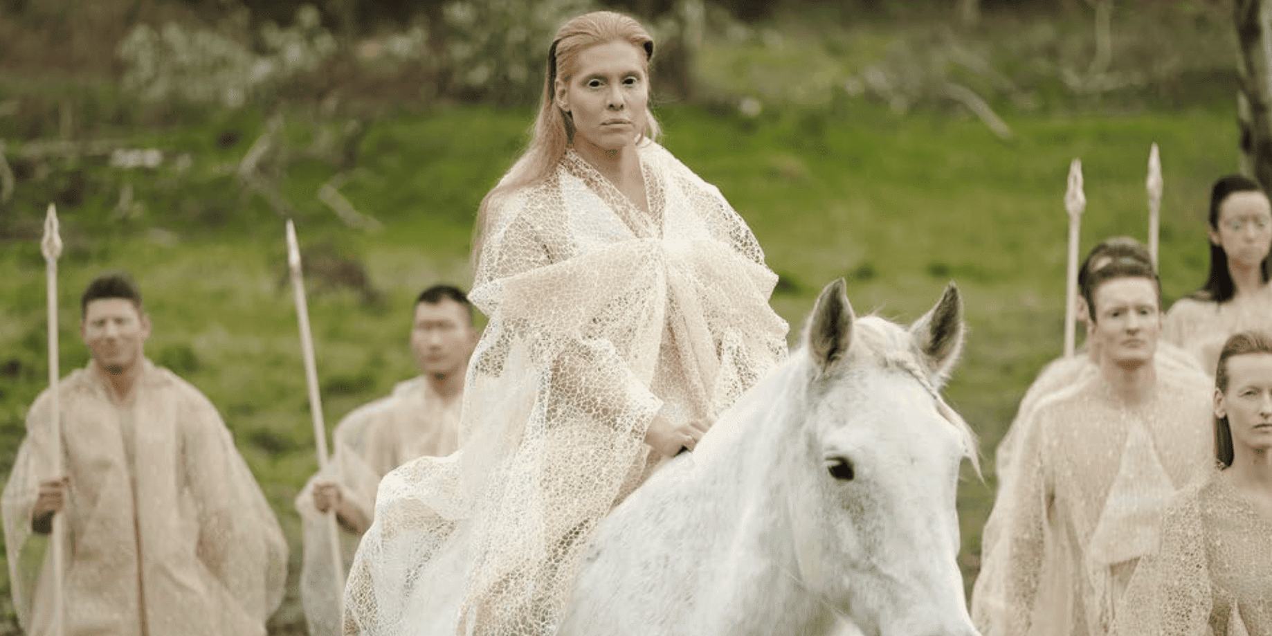 The Fairy Queen (Candis Cayne) rides a horse while surrounded by an army of fairies threateningly holding spears in this image from McNamara Moving Company.