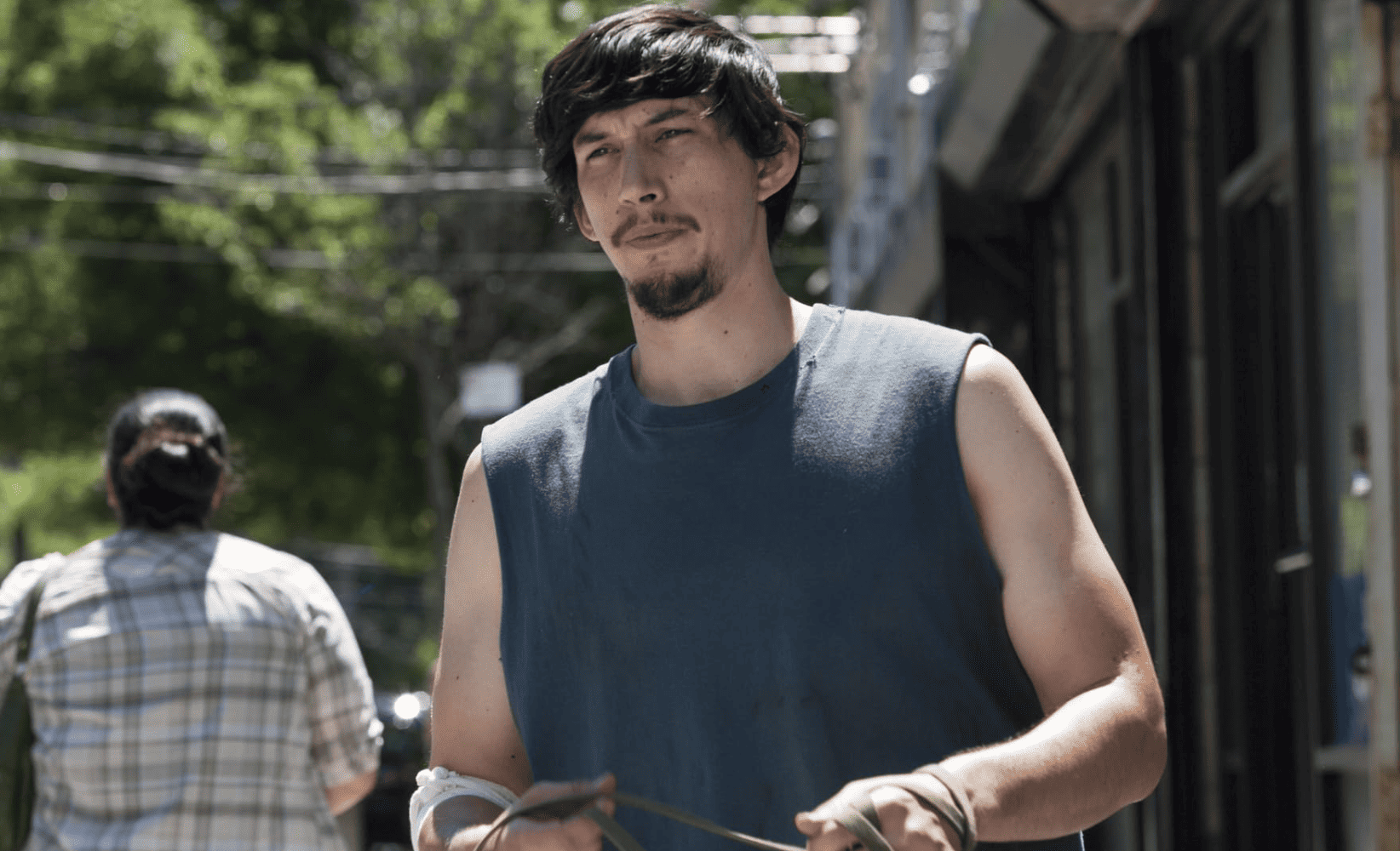 Adam Driver in character walking some dogs and wearing a tank top in this image from Apatow Productions