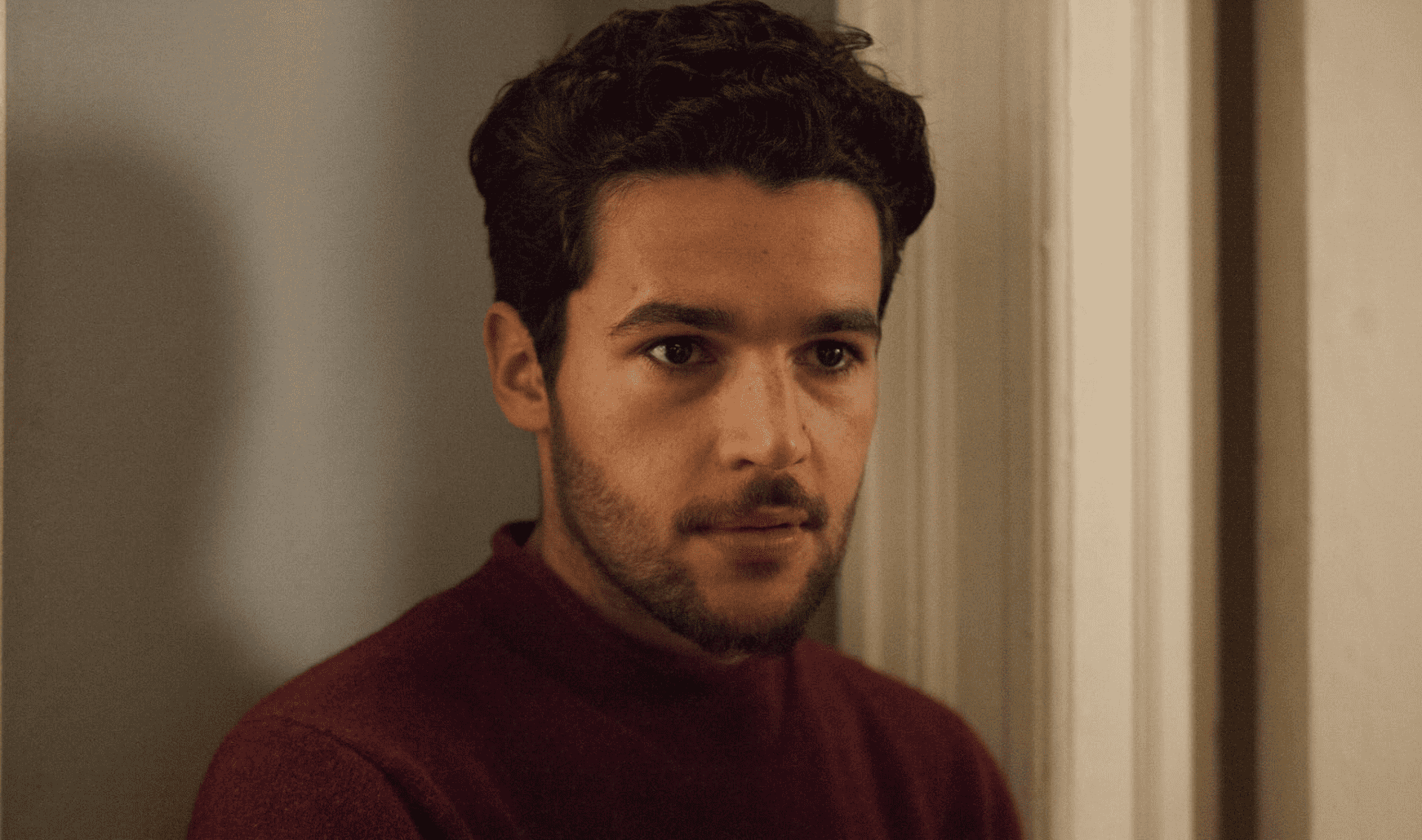 Charlie, played by Christopher Abbott, staring off-camera wearing a red turtleneck sweater in this image from Apatow Productions
