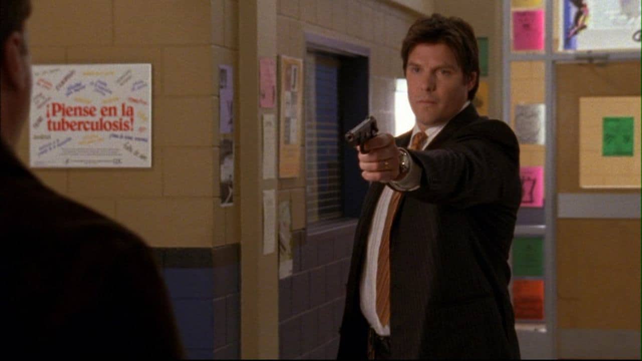 A man holds up a gun in a school in this image from Tollin/Robbins Productions.