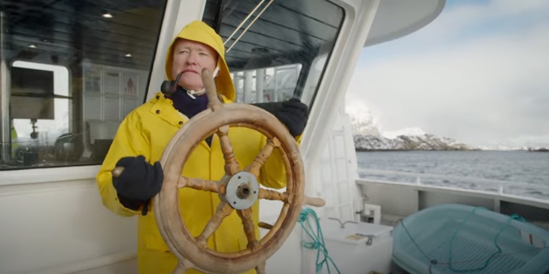 Conan O’Brien is dressed in a yellow raincoat as he steers a boat in this image from Conaco.