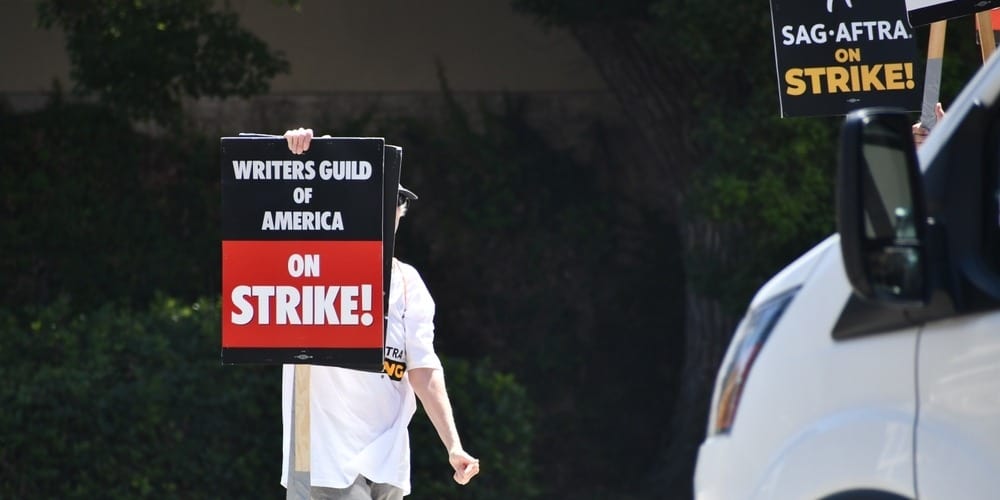 A person crossing the street covered by a picket sign in this image from Shutterstock